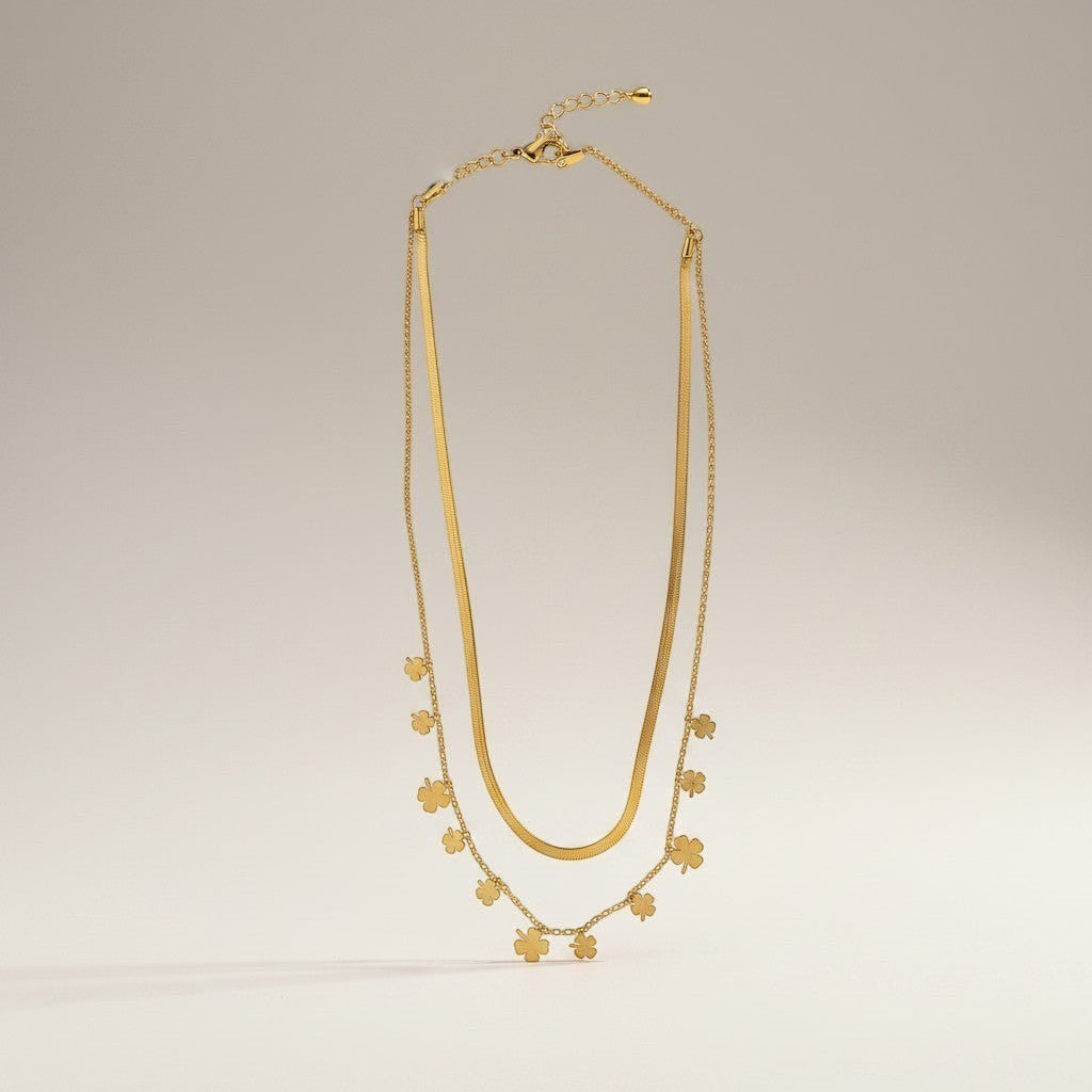 AVIRI gold-tone layered necklace with herringbone chain and clover charms. Adjustable length.