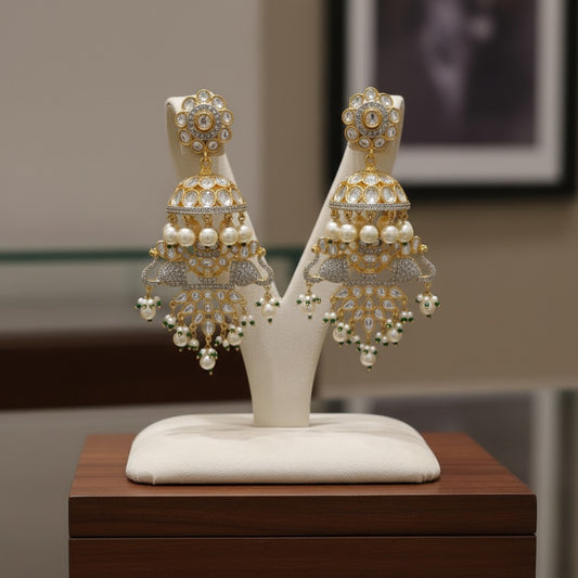 AVIRI gold-plated jhumka earrings with peacock motifs, white stones, pearls, and green beads.