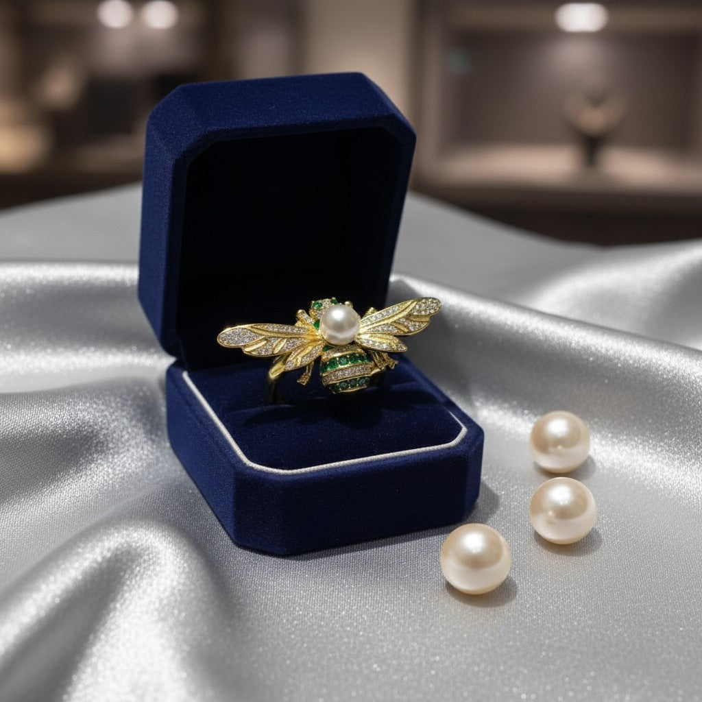 AVIRI gold-tone adjustable bee ring with pearl body, emerald accents, and cubic zirconia wings.