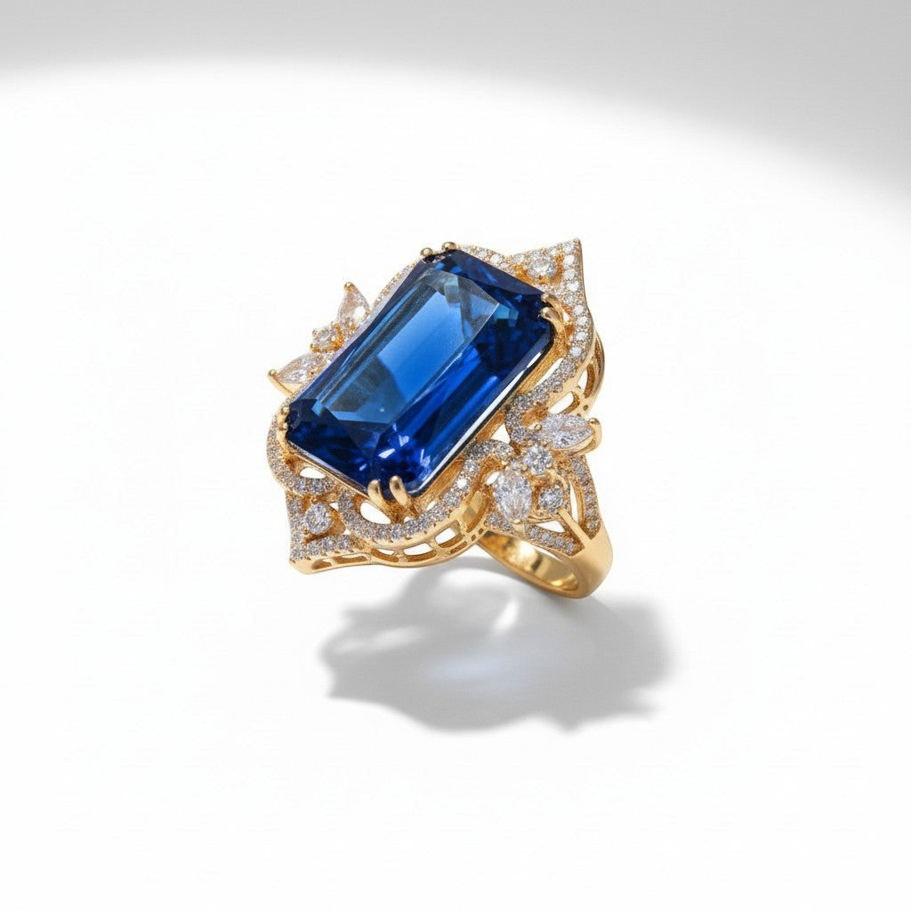 AVIRI statement cocktail ring with large emerald-cut blue gemstone, pavé diamonds, and marquise accents in 14k yellow gold.