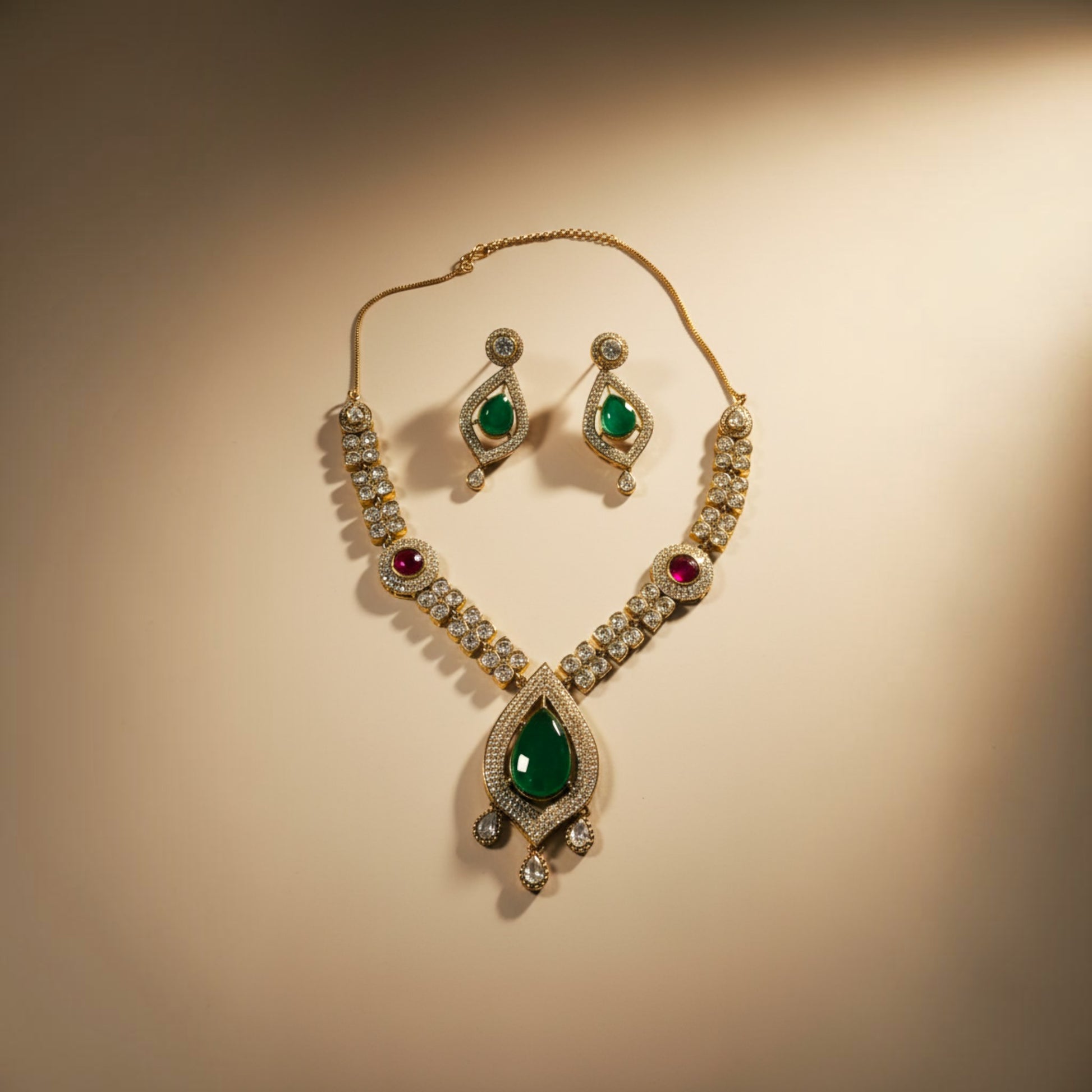 AVIRI traditional jewelry set featuring a teardrop emerald pendant, ruby accents, and crystals on a metallic base.