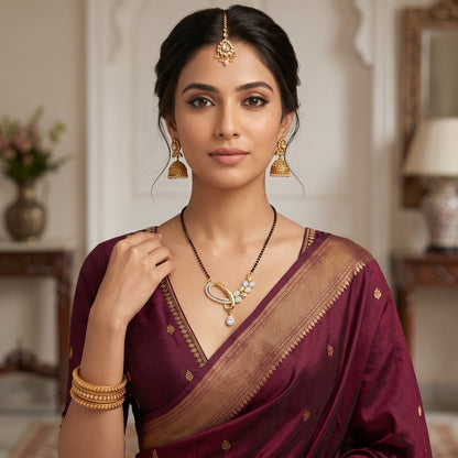 AVIRI gold-toned Mangalsutra set with black beads, stone-studded pendant, and matching drop earrings on a woman in sari