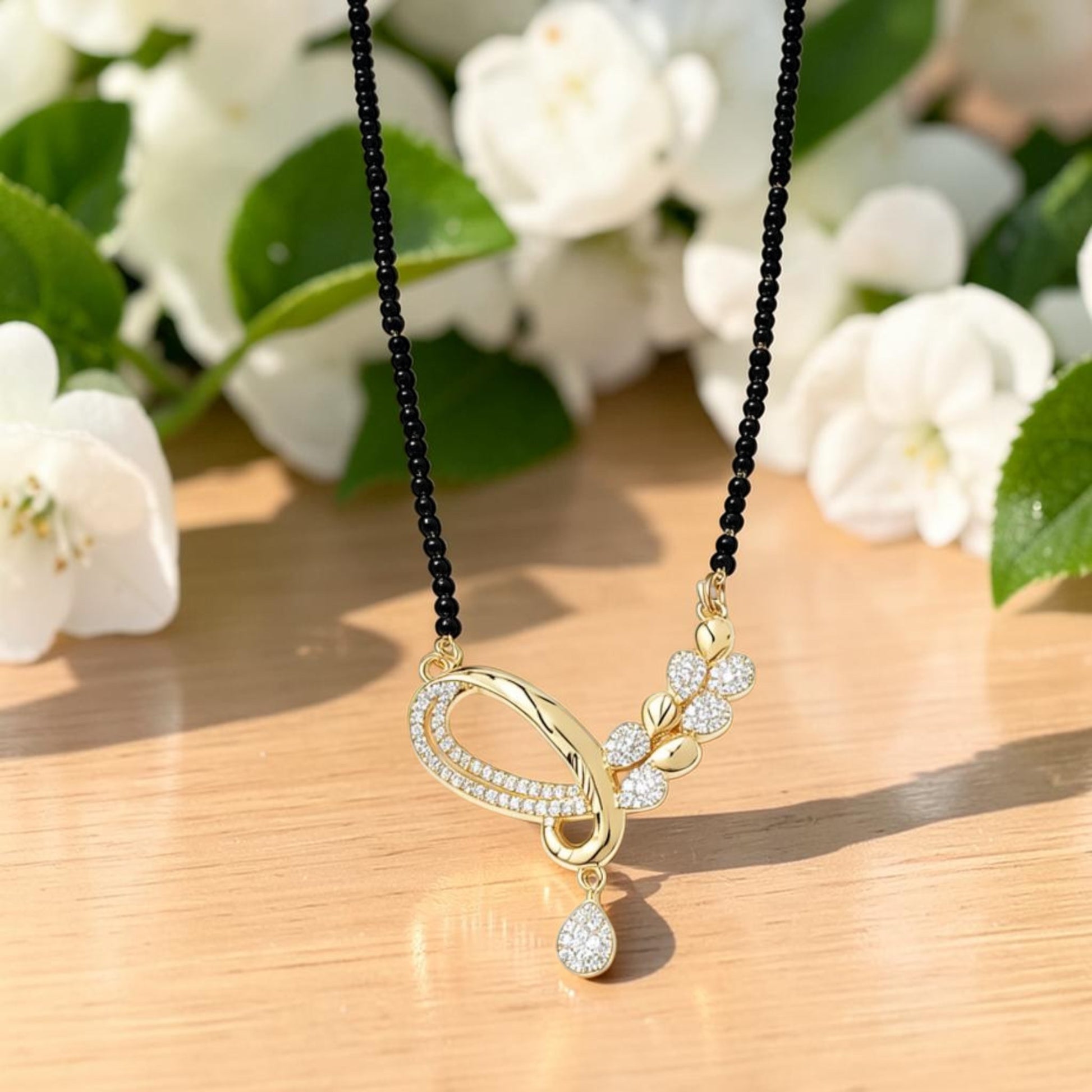AVIRI gold-plated Mangalsutra necklace with black beads and a fluid pendant featuring shimmering white stones