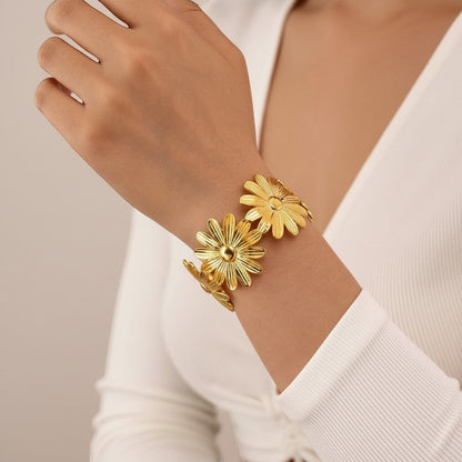 AVIRI gold-tone metal cuff bracelet with detailed daisy flower design, adjustable open cuff.