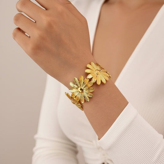 AVIRI gold-tone metal cuff bracelet with detailed daisy flower design, adjustable open cuff.