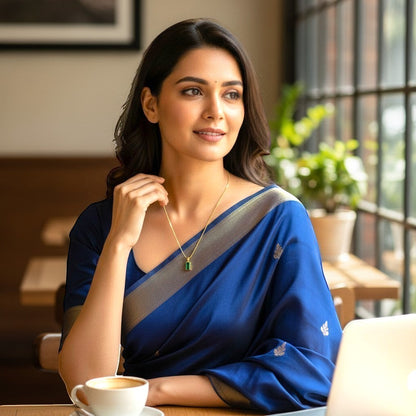 AVIRI gold plated necklace with emerald green rectangular pendant on a woman wearing a blue saree.