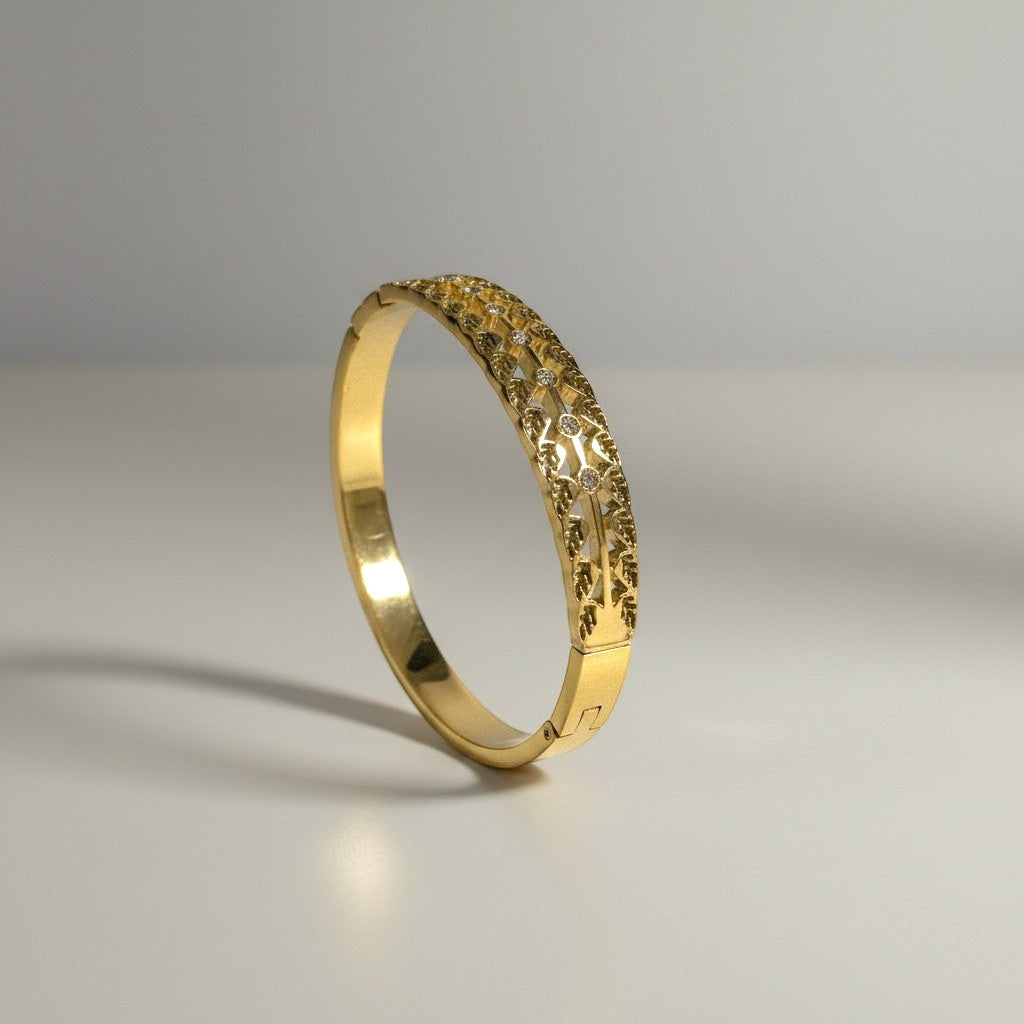 AVIRI gold-tone cuff bracelet with ornate filigree cut-out detailing and a leaf motif.