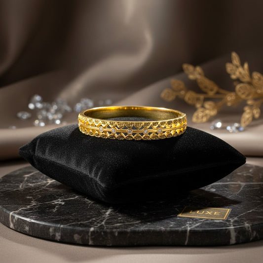 AVIRI gold-tone cuff bracelet with ornate filigree cut-out detailing and a leaf motif. Polished finish.