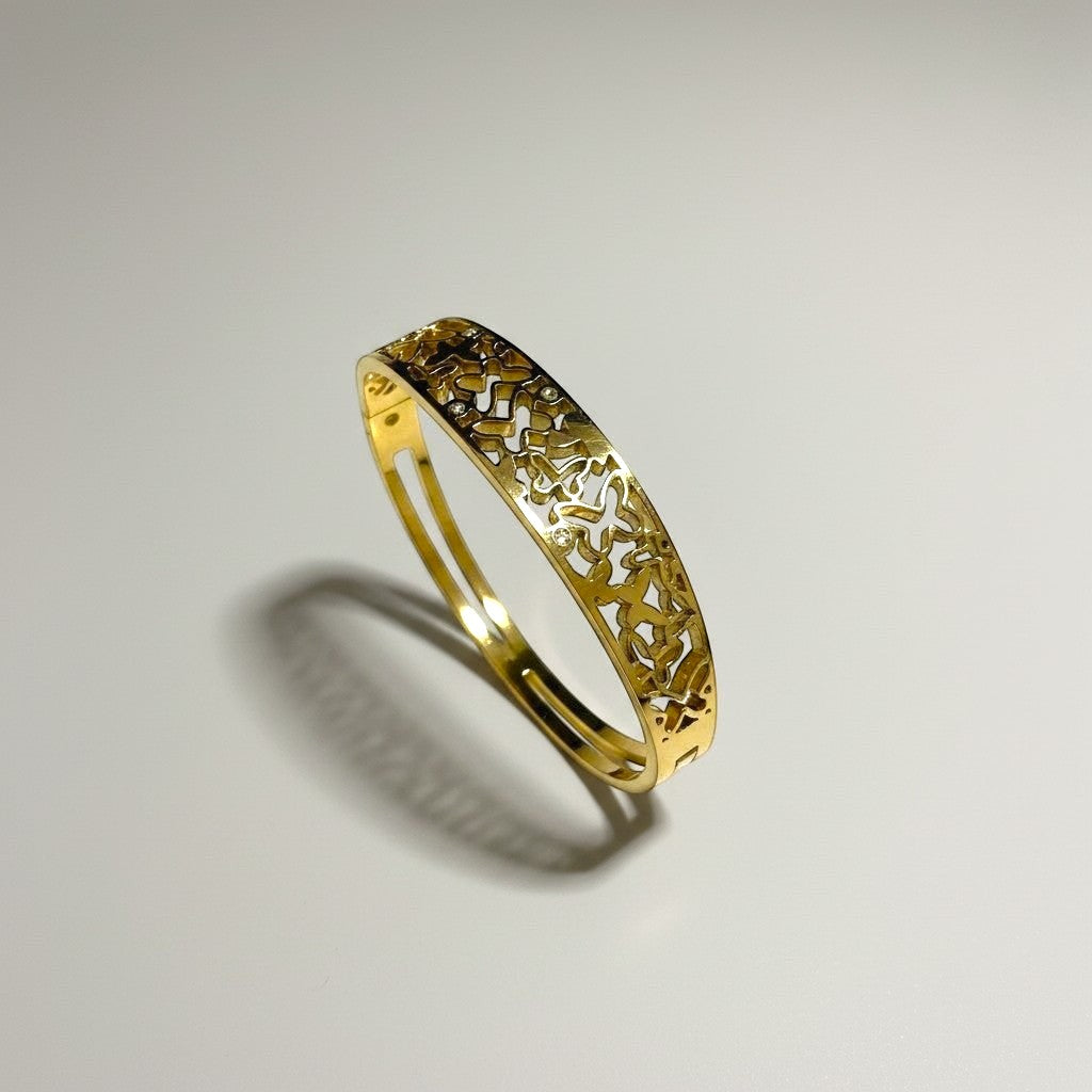 AVIRI gold-tone metal cuff bracelet with ornate filigree openwork design and polished finish.