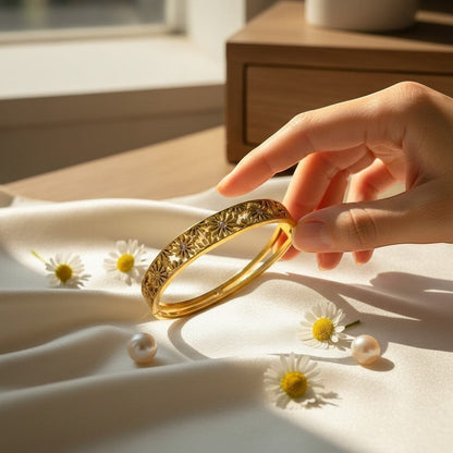 AVIRI gold-tone hinged bangle bracelet with floral cut-out detailing and a polished finish.