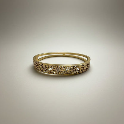 AVIRI gold-tone hinged bangle bracelet with intricate floral cut-out detailing and a polished finish.