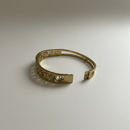 AVIRI gold-plated hinged bangle bracelet with intricate floral cut-out design and secure clasp.