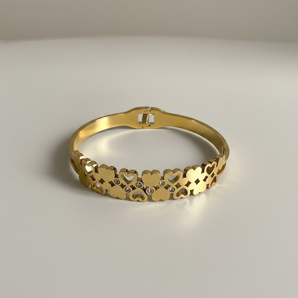 AVIRI gold-tone stainless steel cuff bracelet with interlocking hearts and cubic zirconia accents.