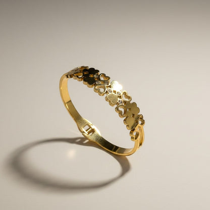 AVIRI gold-tone stainless steel cuff bracelet with interlocking hearts and cubic zirconia accents. Adjustable.