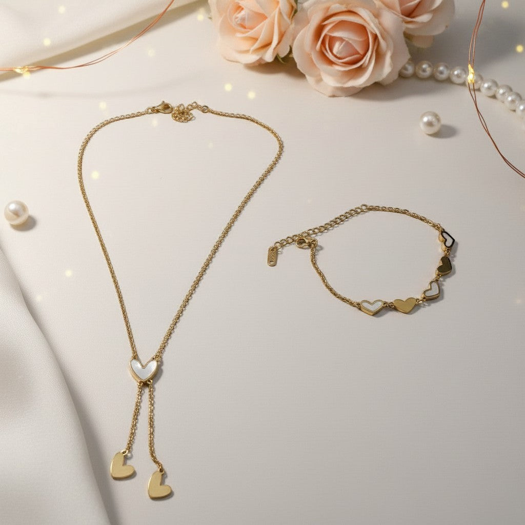 AVIRI gold-tone stainless steel necklace and bracelet set with heart charms. Necklace has a lariat design with a white heart pendant.
