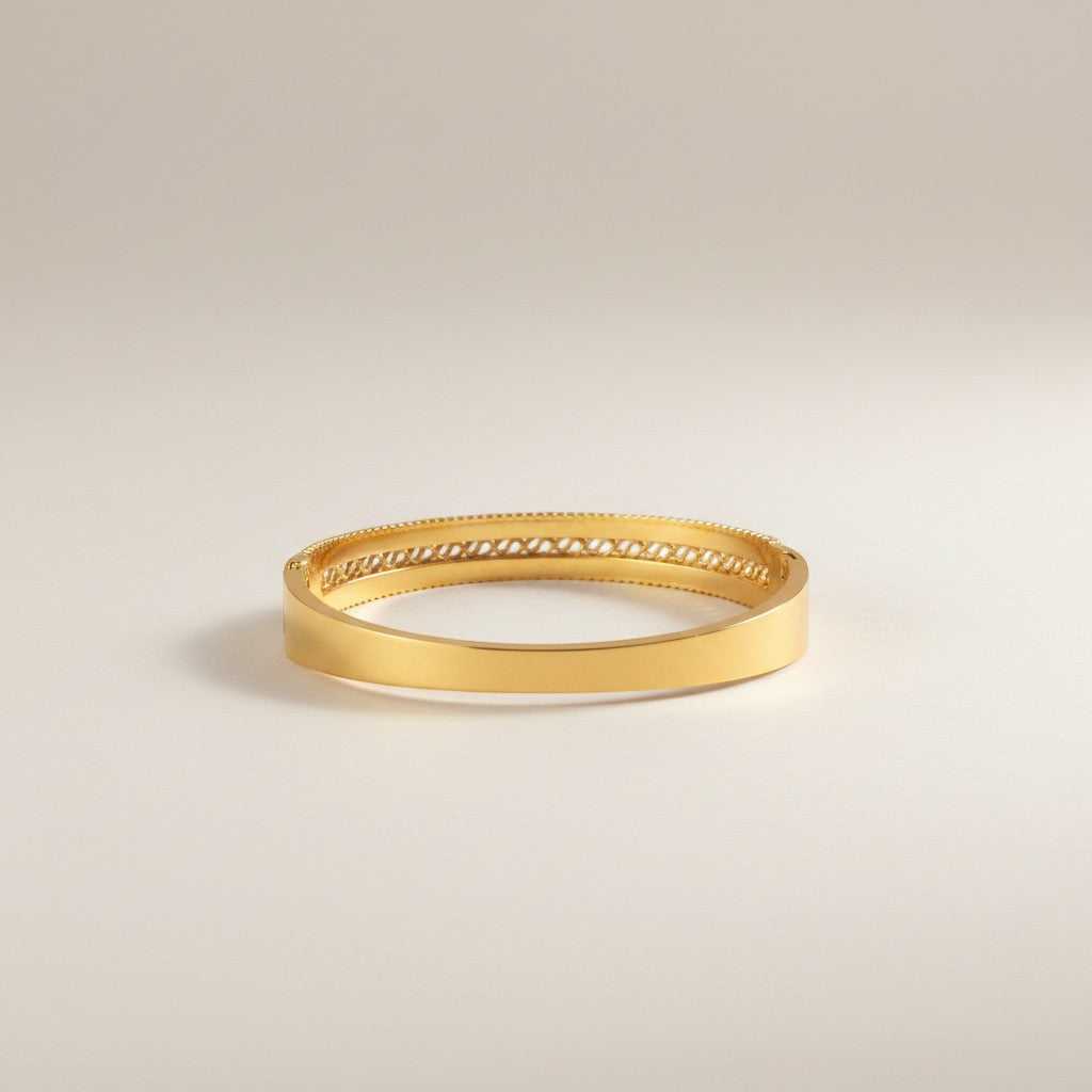AVIRI gold-plated bangle with intricate swirling patterns and cubic zirconia stones. Features beaded edges and a traditional design.
