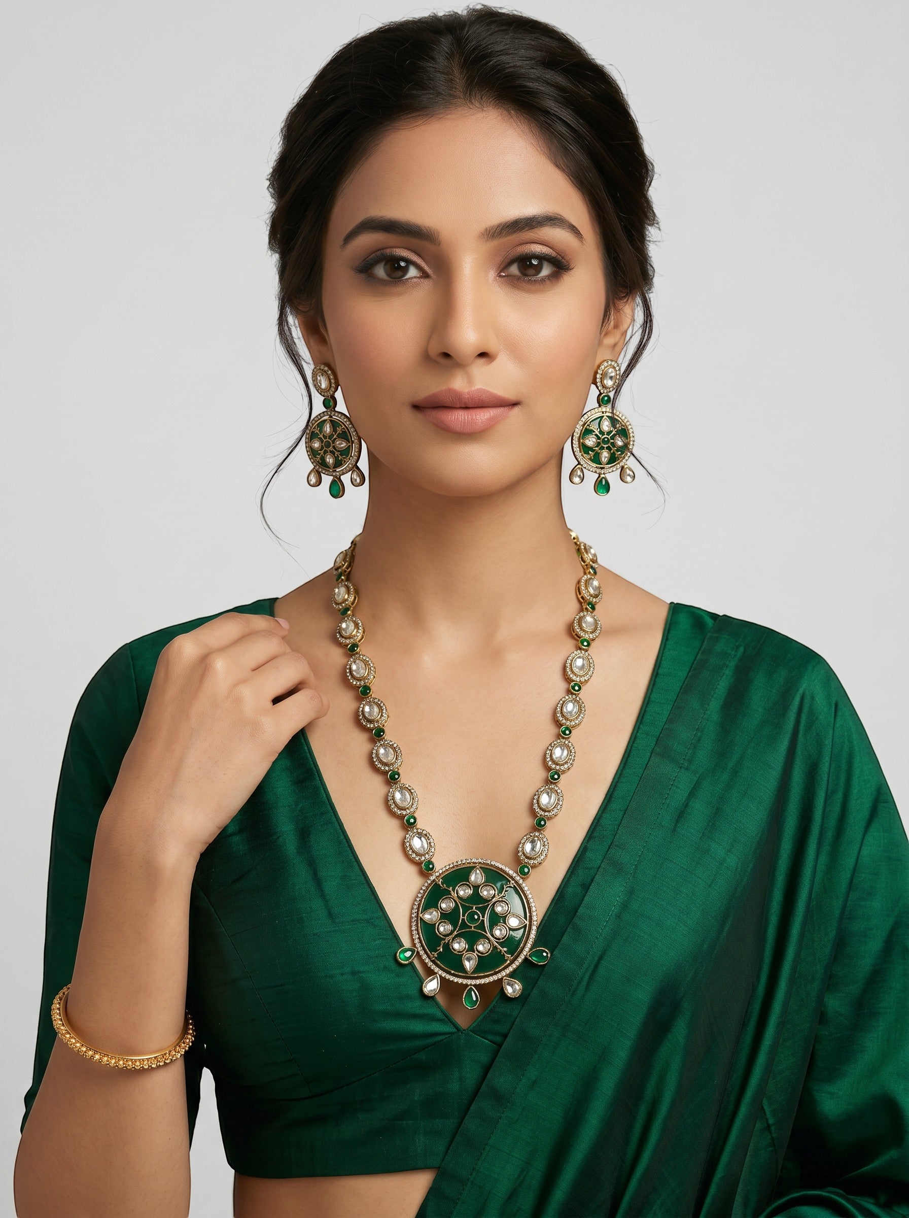 AVIRI traditional jewelry set with green enamel, white stones, and antique gold finish on a woman in a green saree.