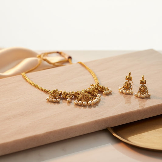 AVIRI traditional gold necklace and pearl drop earrings set with intricate Indian motifs. Perfect for festive wear.