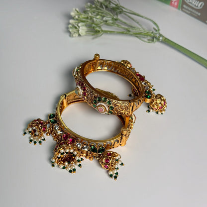 AVIRI traditional gold-tone hinged bangle bracelets with red and green Kundan stones, floral filigree, and dangling jhumkas