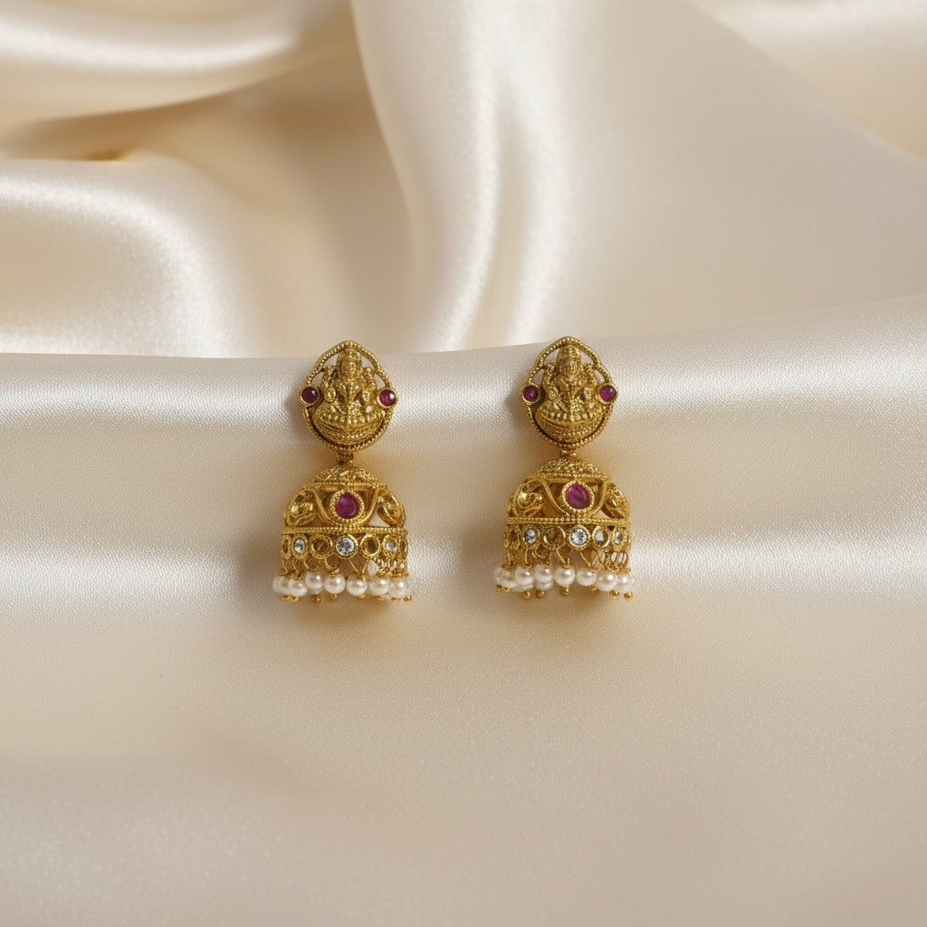 AVIRI Traditional Lakshmi Jhumka earrings with pearls, ruby accents, and antique gold finish.