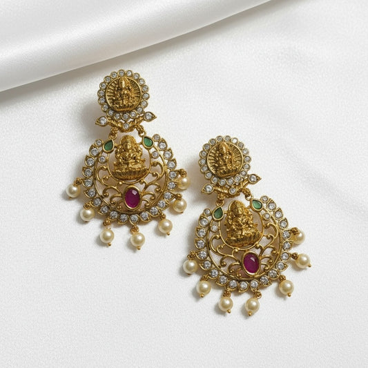 AVIRI traditional Lakshmi motif dangle earrings with pearls, emeralds, and ruby red gemstone. Gold-toned metal.