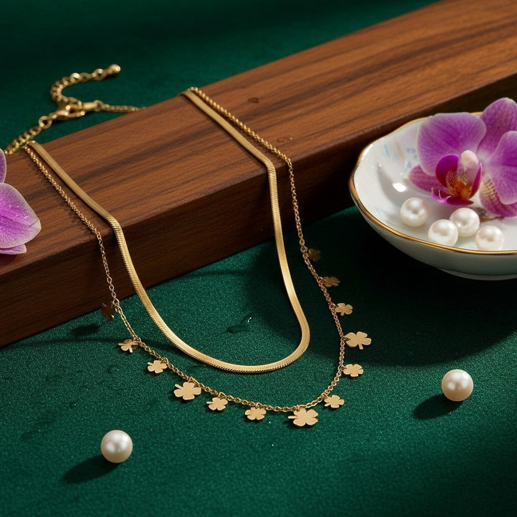 AVIRI gold-tone layered necklace with herringbone chain and clover charms. Adjustable length.