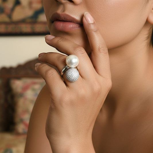 AVIRI pearl and diamond sphere ring with bypass design in gold. Features a large pearl and a textured sphere with sparkling diamonds.
