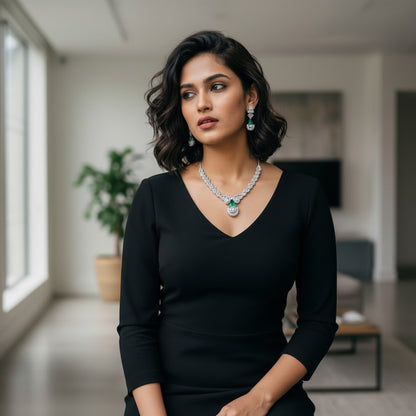 AVIRI statement necklace and earring set with emerald green gemstones and clear stones, worn by a model.
