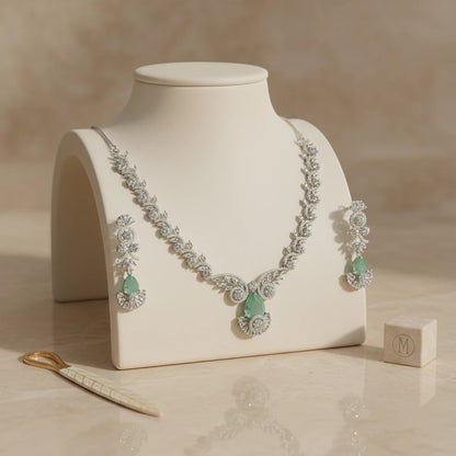 AVIRI statement necklace and earring set with emerald-green gemstones and clear accent stones, crafted in silver-tone metal.