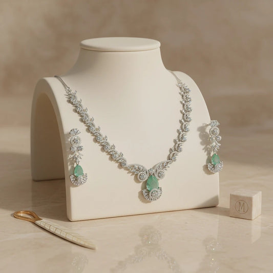 AVIRI statement necklace and earring set with emerald-green gemstones and clear accent stones, crafted in silver-tone metal.