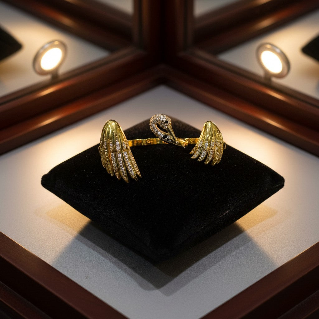 AVIRI gold-tone metal ring with swan and wings design, adorned with clear crystals.