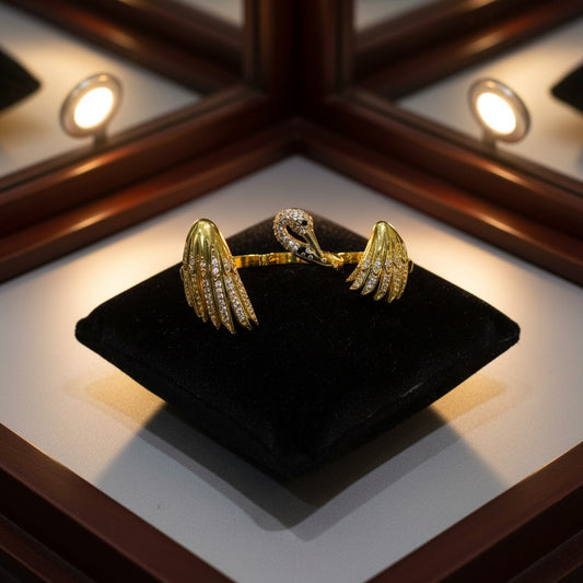 AVIRI gold-tone metal ring with swan and wings design, adorned with clear crystals.