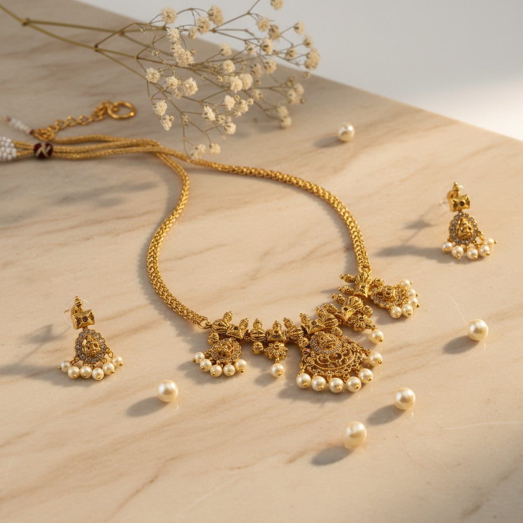 AVIRI traditional gold necklace and earring set with pearl drops and intricate motifs. Gold-plated.