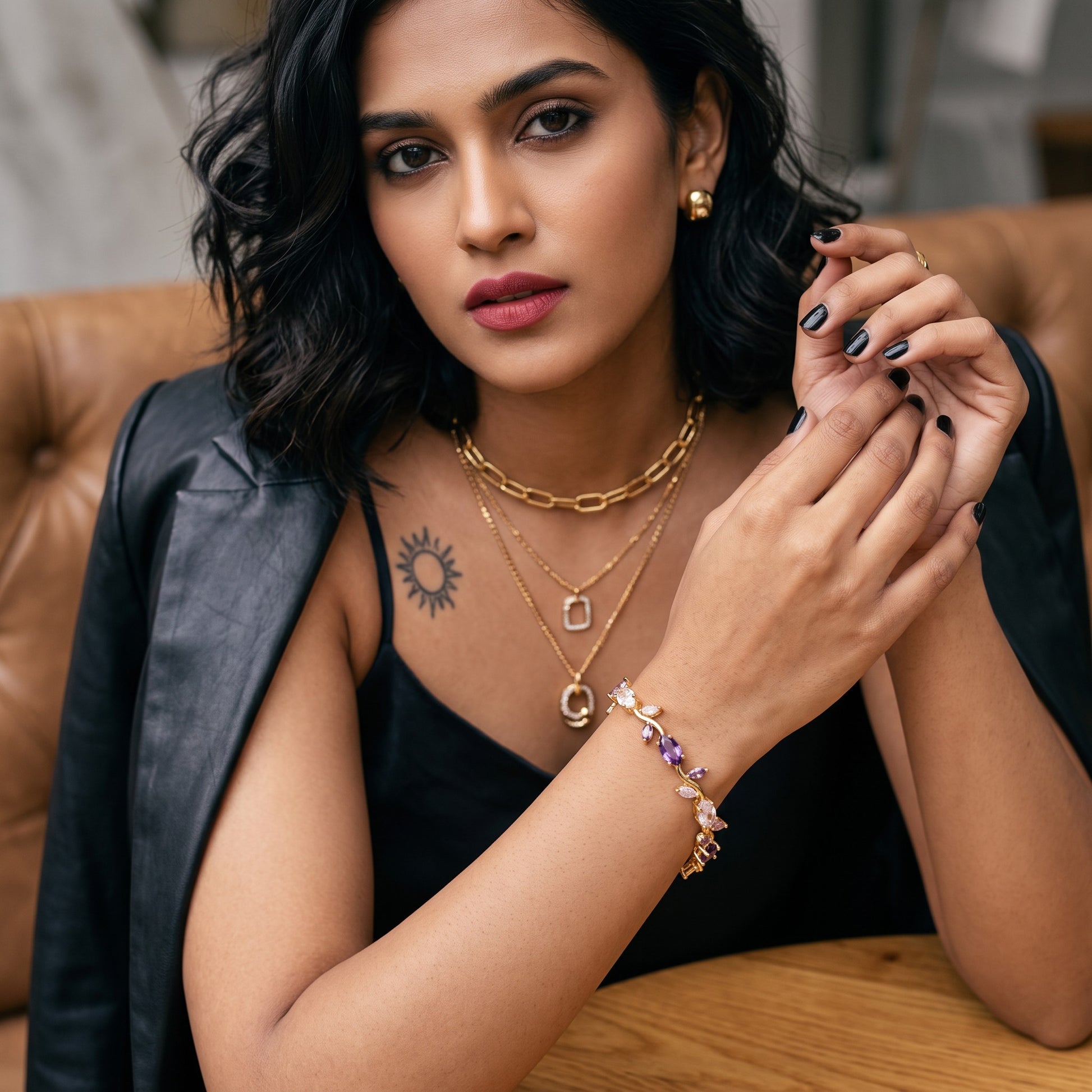 AVIRI Tulip Bracelet in 18K gold-plated metal with multi-colored gemstones worn by a woman in a black outfit.